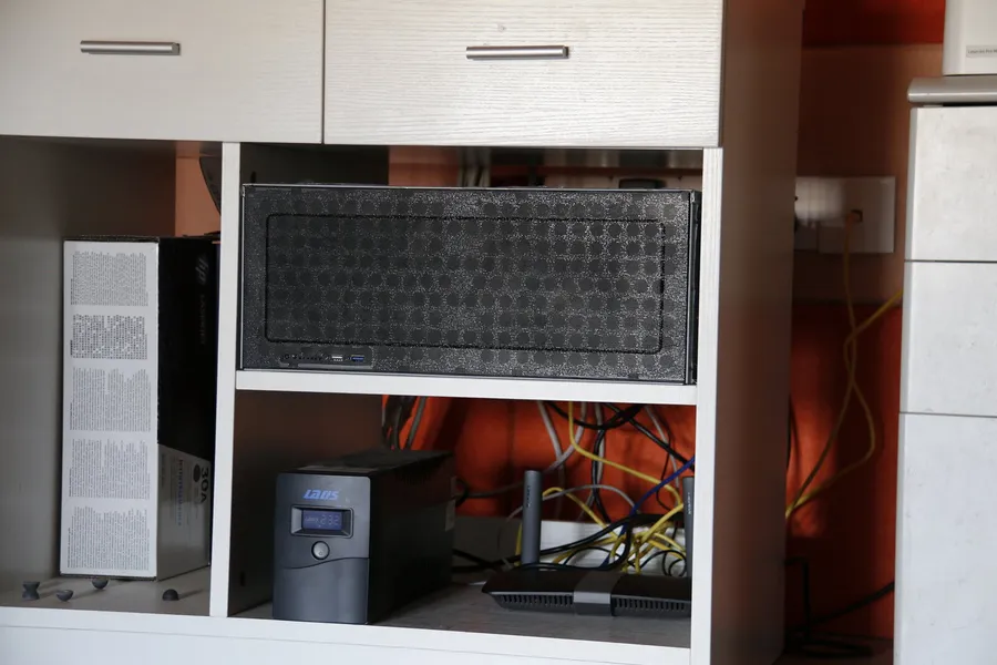 A home server, UPS, and router arranged on a shelf